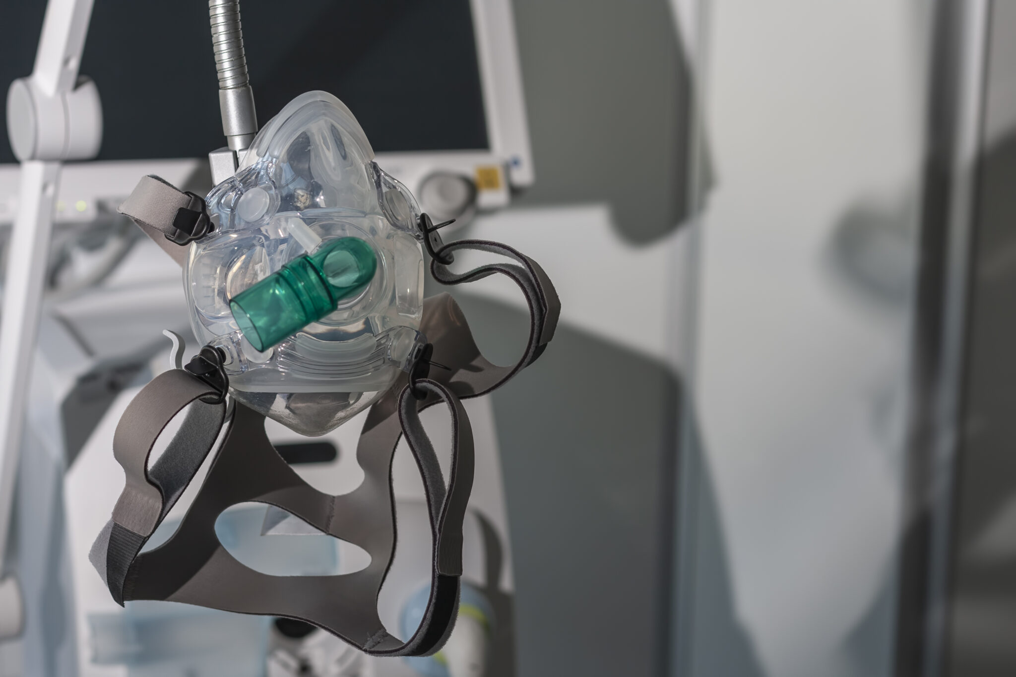 Non-invasive ventilation face mask, on background medical ventilator in ICU in hospital. NIV Mask hanging off a stand